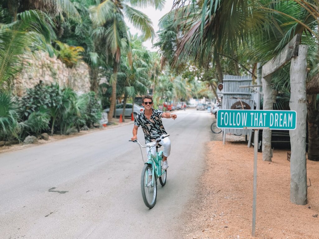 A person cycling and showing a sign board - "Follow that dream"