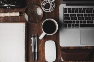 
a book, coffee mug, laptop, 2 pens, magnifying glass, charging cables, diary on the table