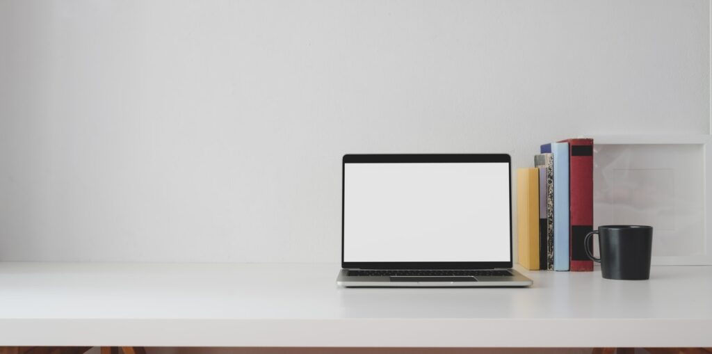 A laptop, 5 books and a coffee mug at the table