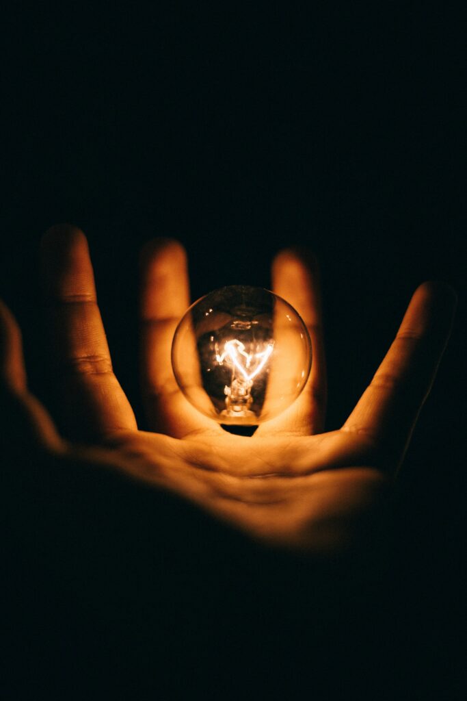 A person holding a lit bulb in the palm