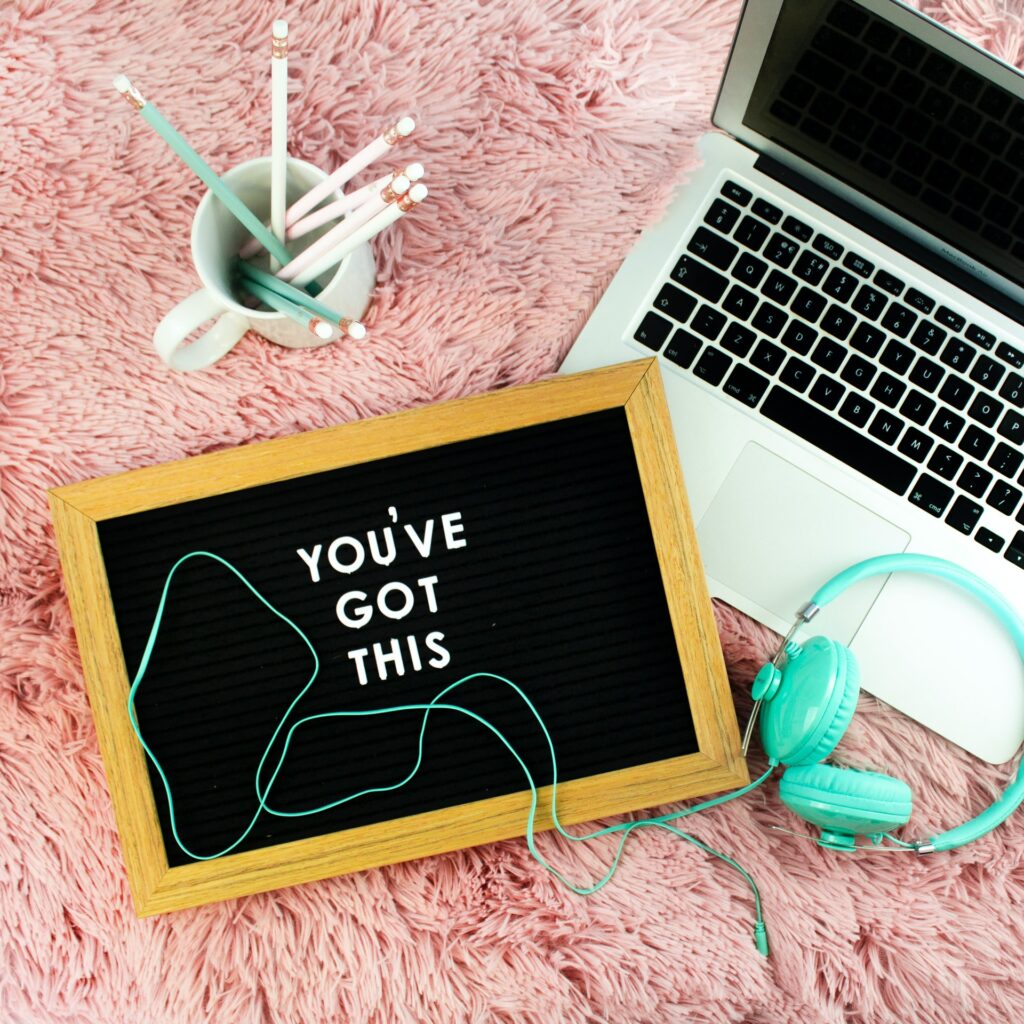 A laptop, a slate, pencil stand and headphones on pink carpet