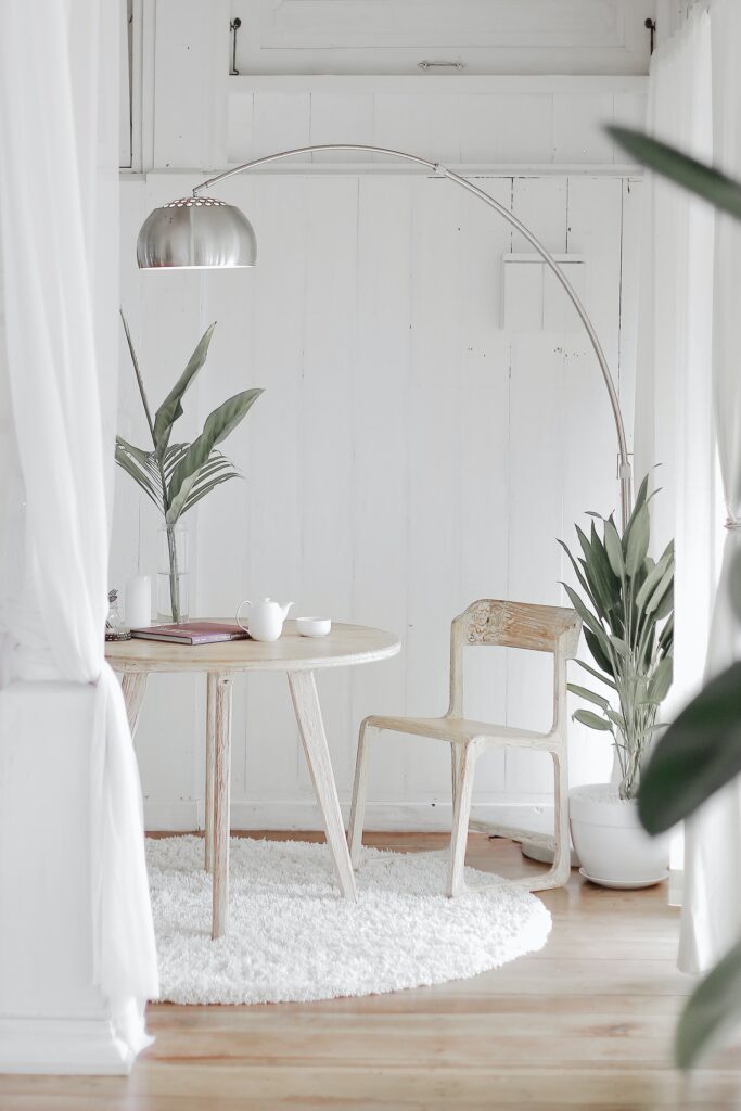 An image showcasing  a table and a chair with lamps and planters adorning the area.