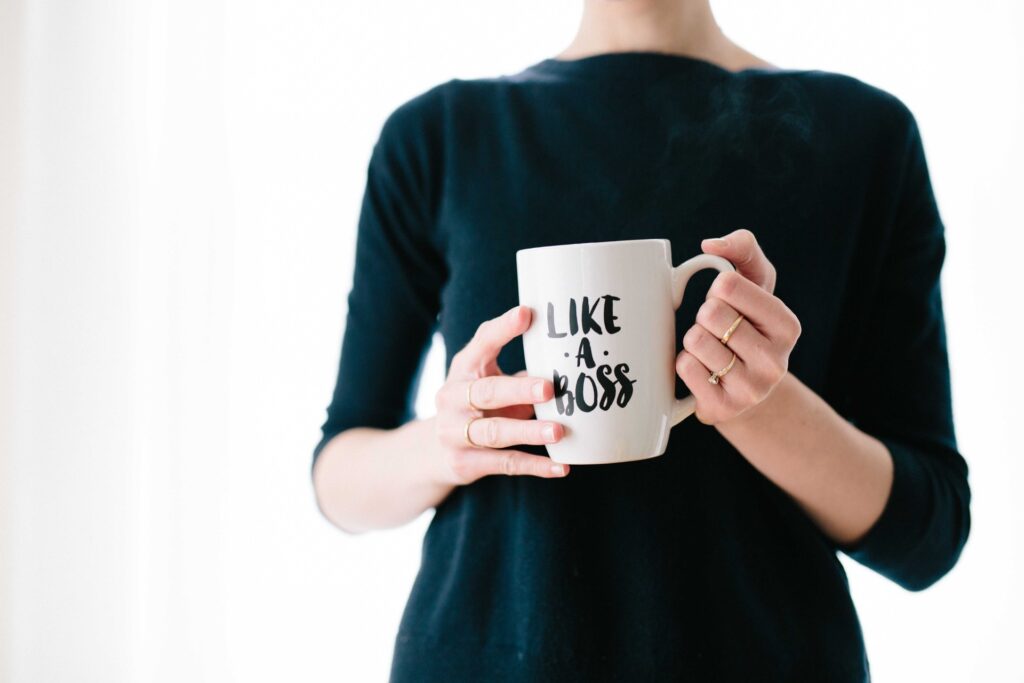 A lady holding a coffee mug which reads 'Like a Boss'